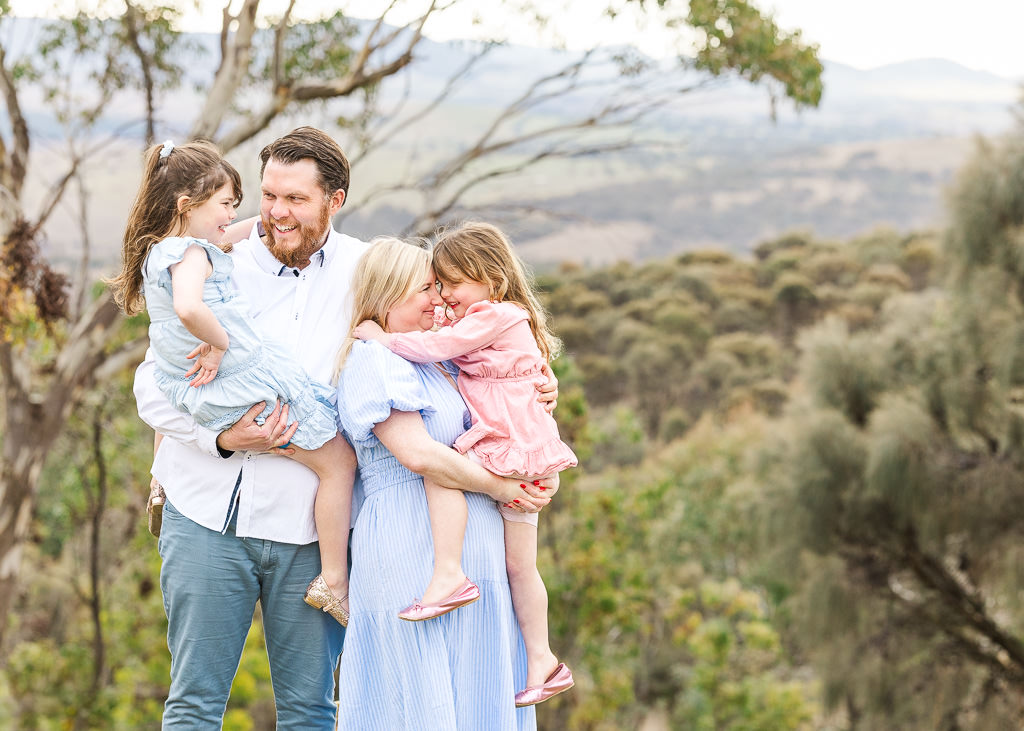 Family holding young daughters during a photo session at Mt Stromlo, Canberra