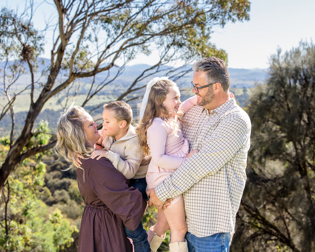Family pictured among valley viewed during a photo session at Mt Stromlo, Canberra