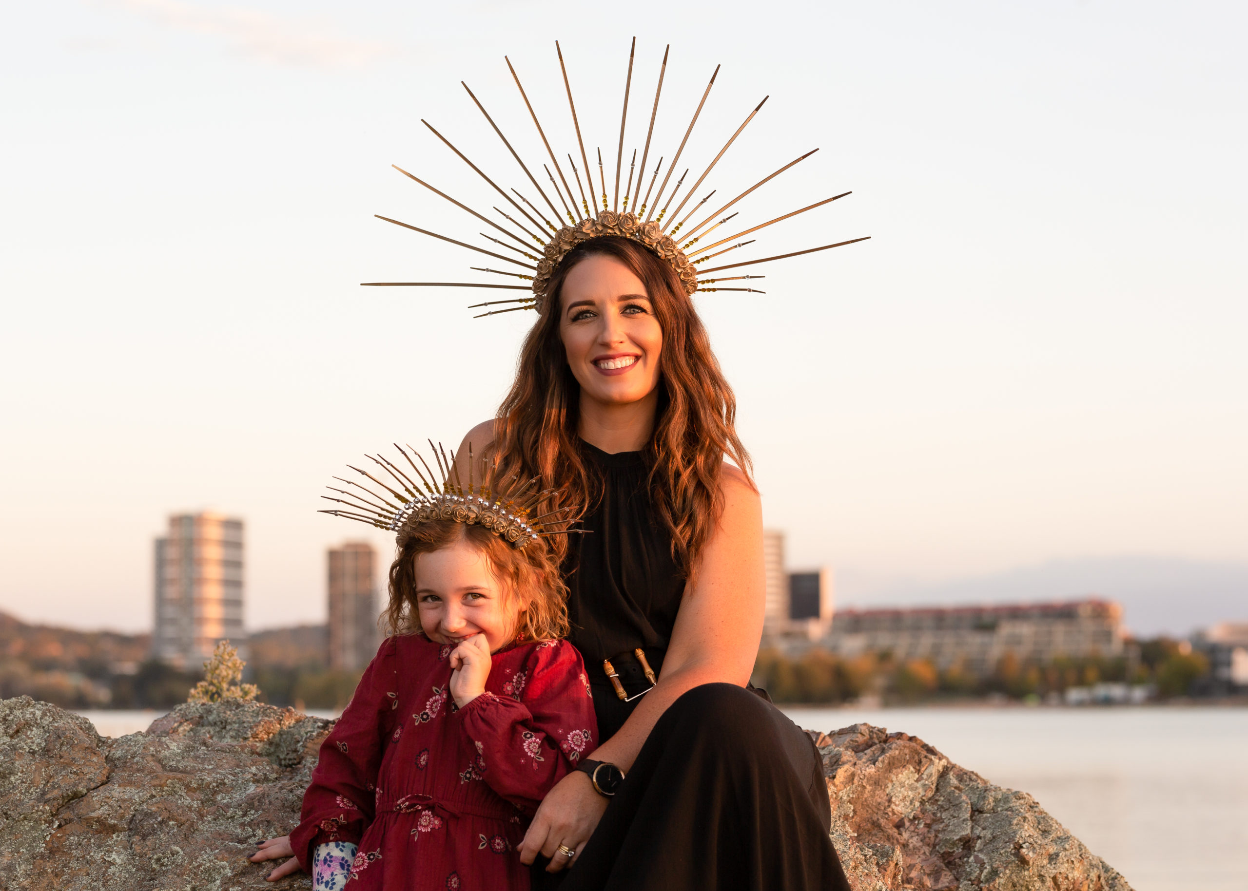 Mother and daughter wearing crowns by a lake