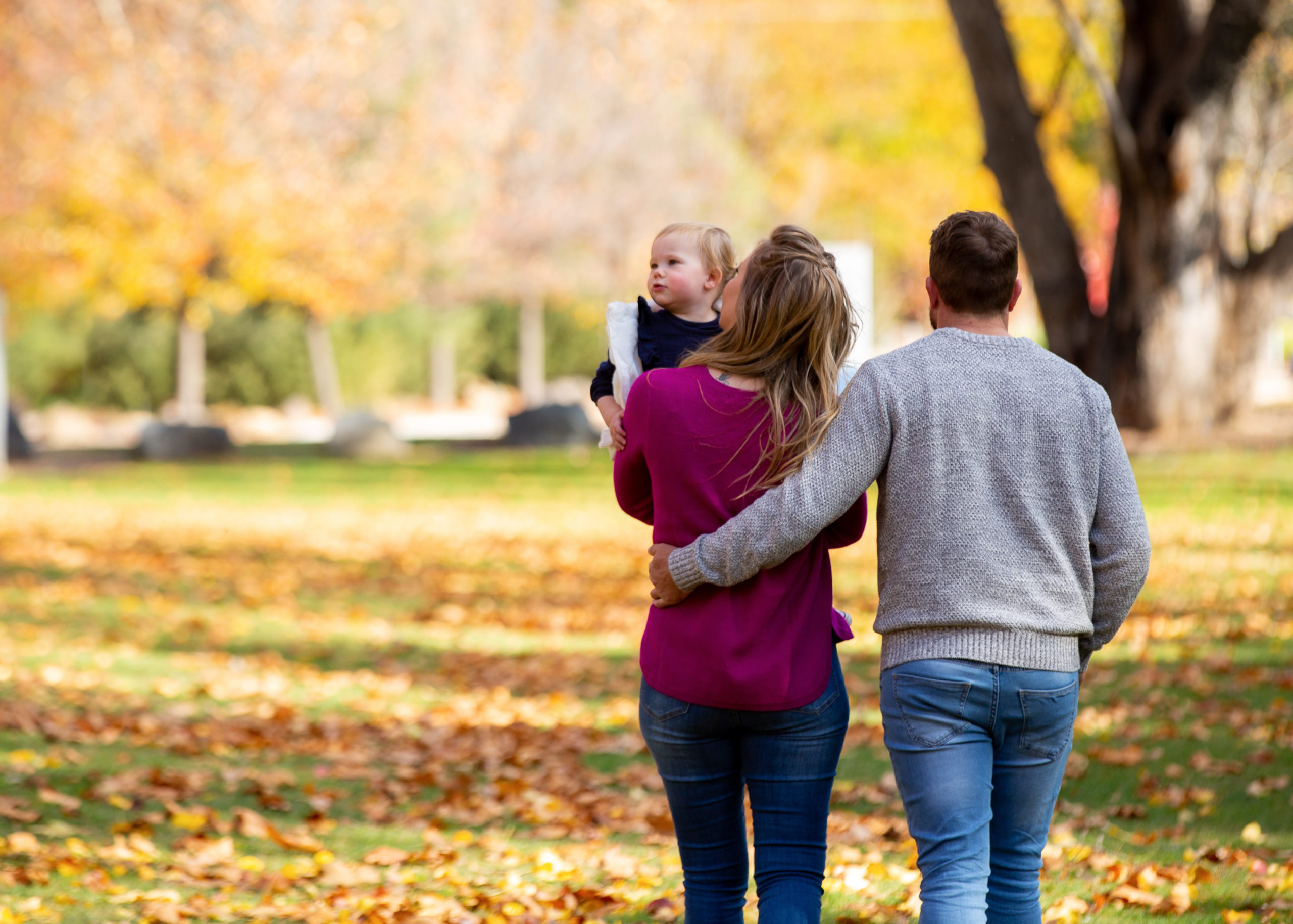 Family walking through autumn leaves