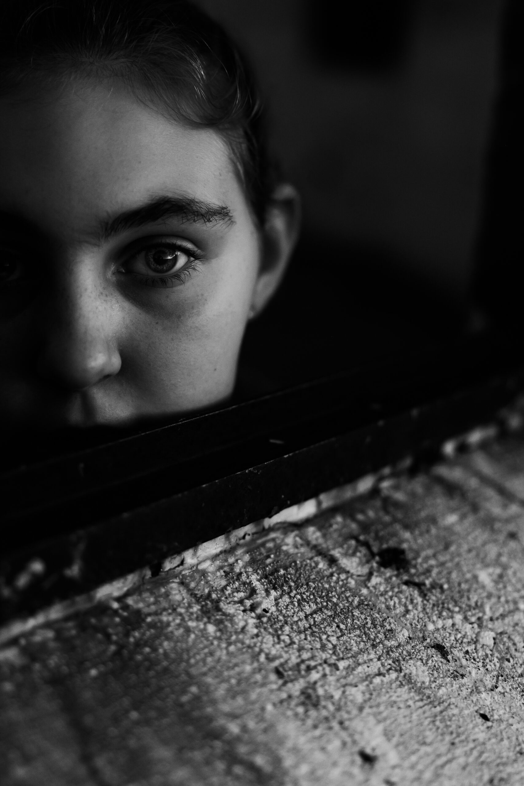 Young girl looking at camera out a window damaged by bushfire