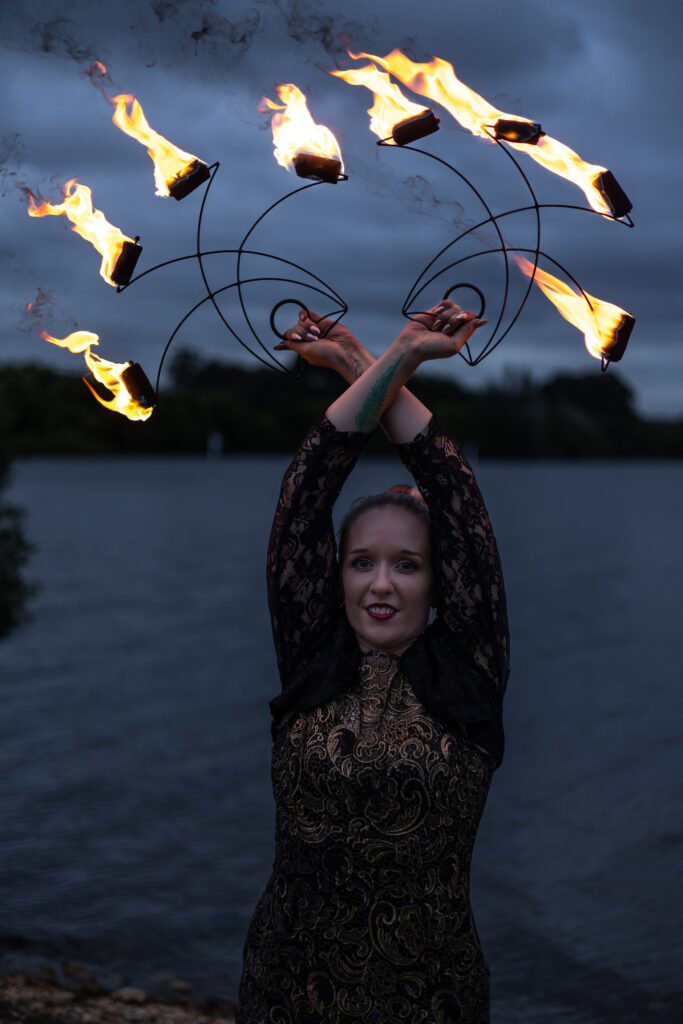 Woman standing by a lake - fire twirling photography