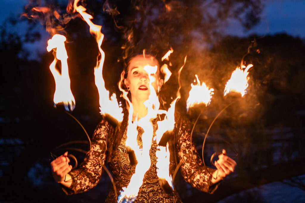 Photograph of a woman's face illuminated by fire twirling