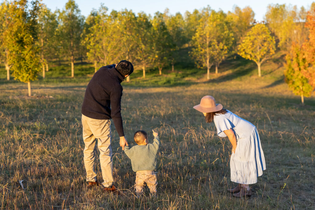 Family with man, wife and toddler pointing to trees in the distance.