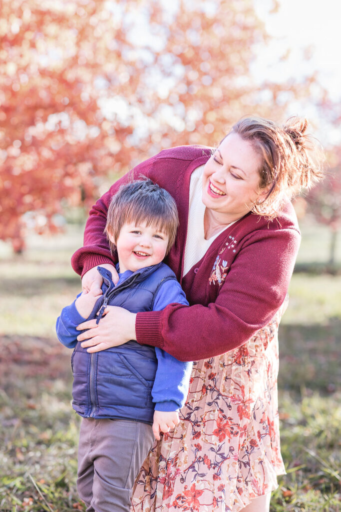 Mother hugging son with autumn leaves behind them at National Arboretum Canberra