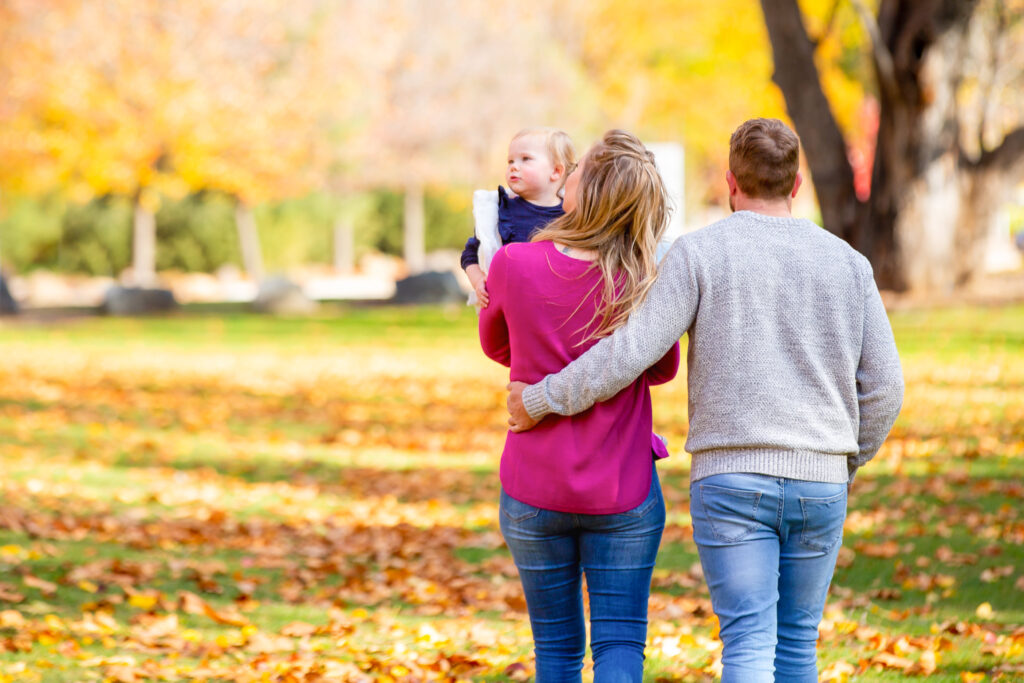 Family with young child looking at autumn trees, Cotter Reserve, Canberra
