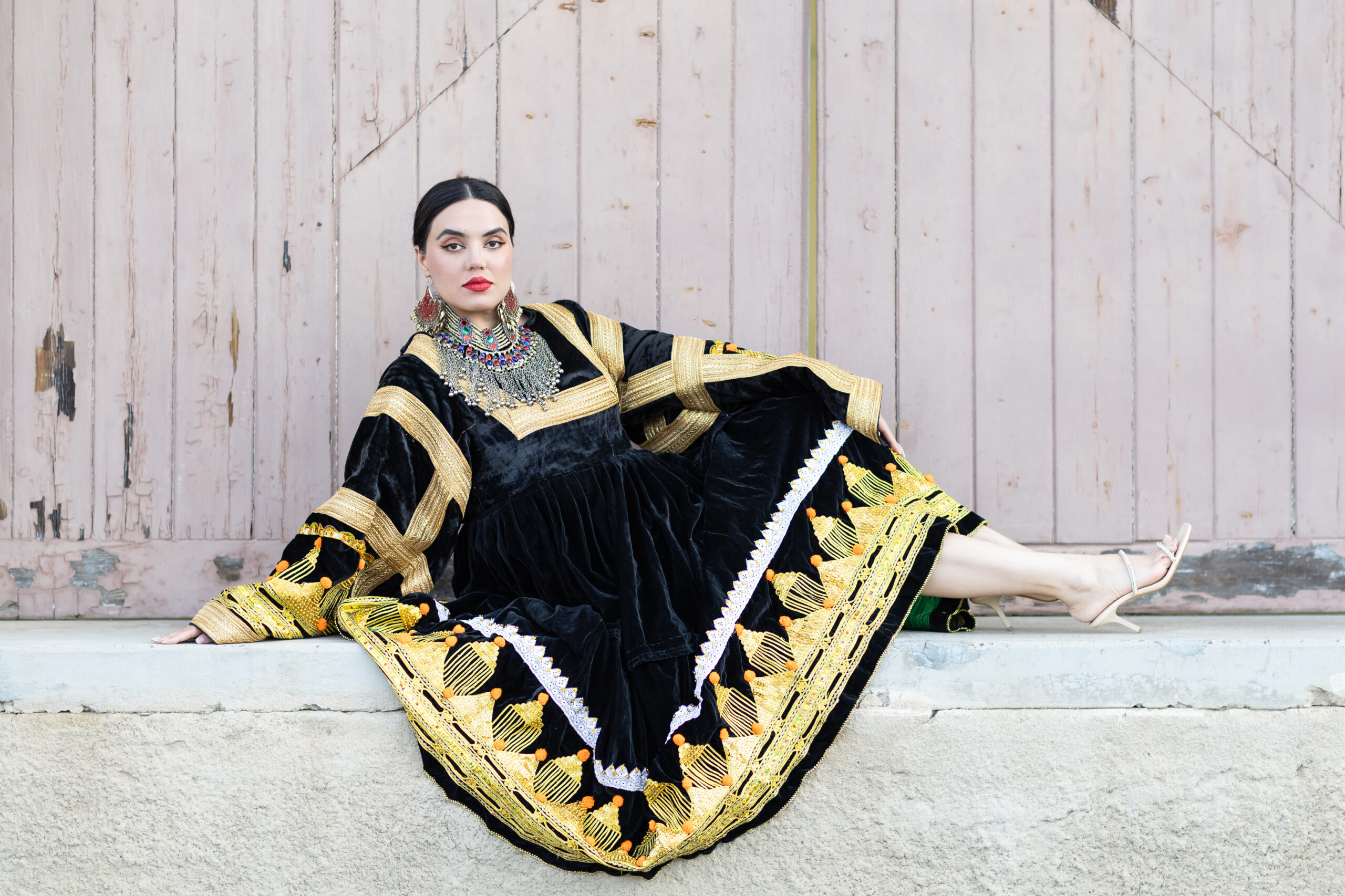 Woman wearing Afghan-inspired RAAZ brand dress, leaning against a door in Kingston, Canberra