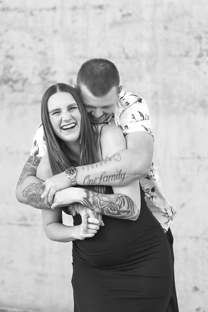 Mother-to-be embraced by her partner during a maternity photo session at Mt Stromlo, Canberra