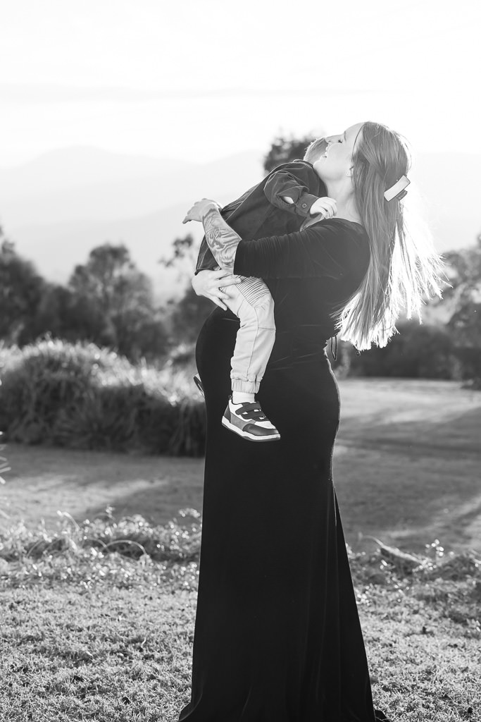 Mother-to-be holding her young son during a maternity photo session at Mt Stromlo, Canberra